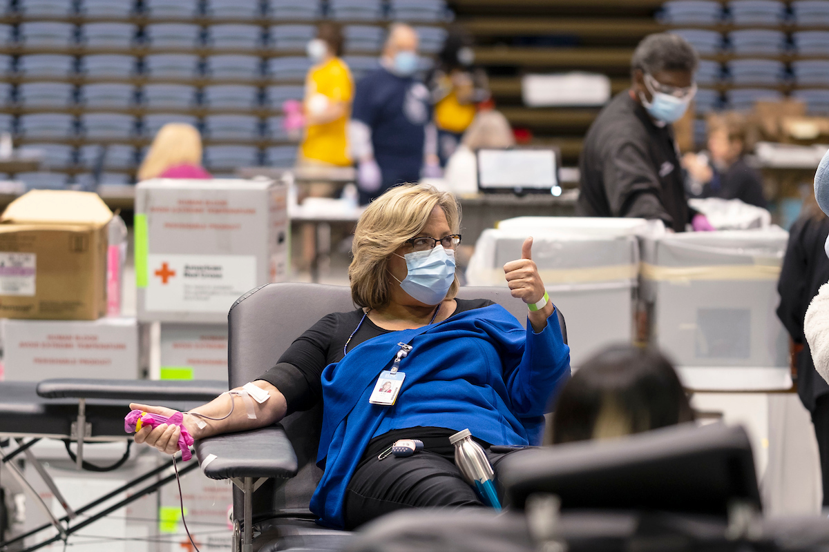 Woman shares a thumbs up while donating blood 