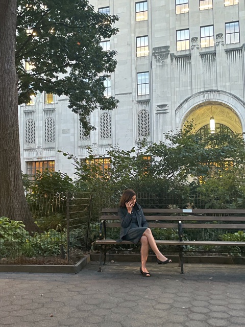Governor Hochul sits on a park bench outside on a phone call