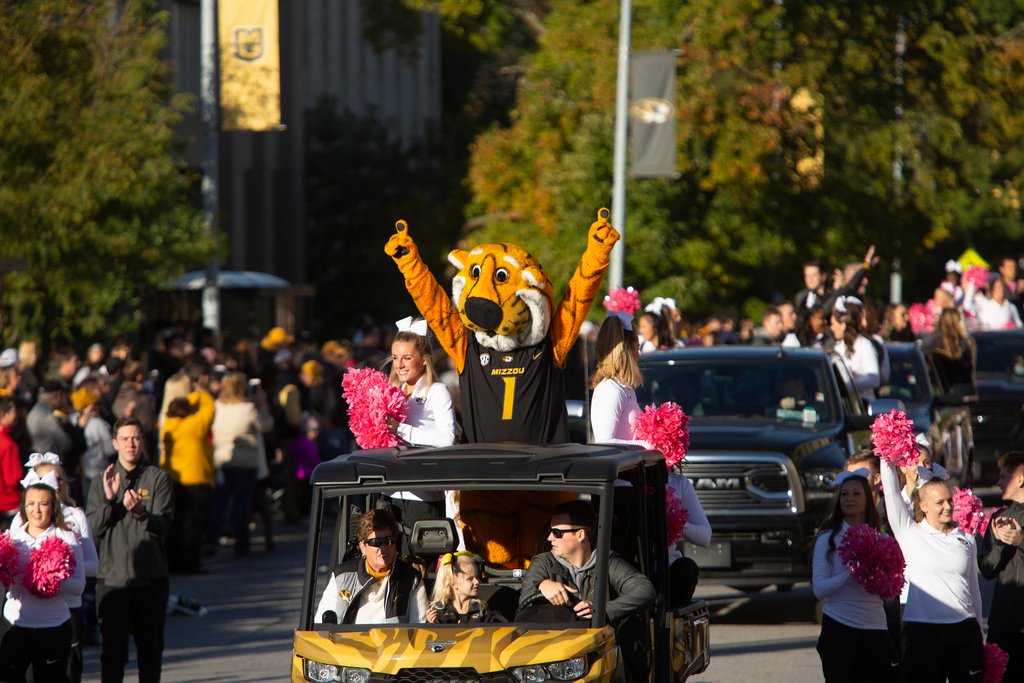 Truman in the parade with his arms stretched into the air while riding in a car