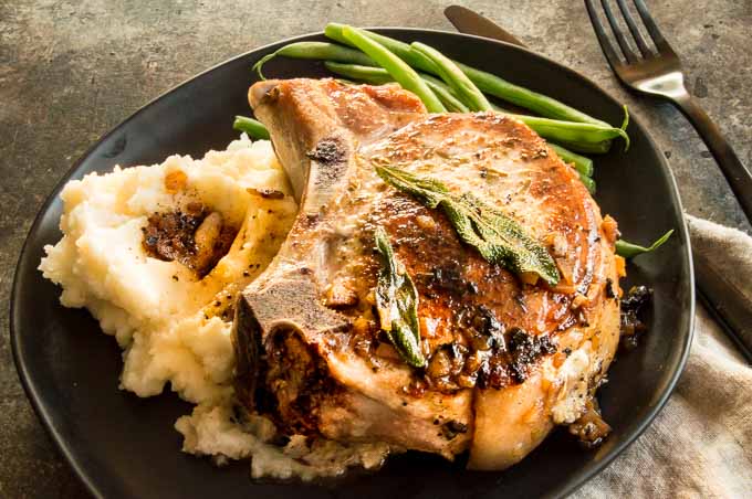 Apple Stuffed Pork chops are filled with hints of apples, mushrooms and creamy cheese.  Easy Gourmet meal to make for weeknight entertaining.  Perfect alternative to Thanksgiving turkey. #stuffedpork #turkeyalternative, #appleweek #applestuffedporkchops westviamidwest.com/apple-herb-stu…