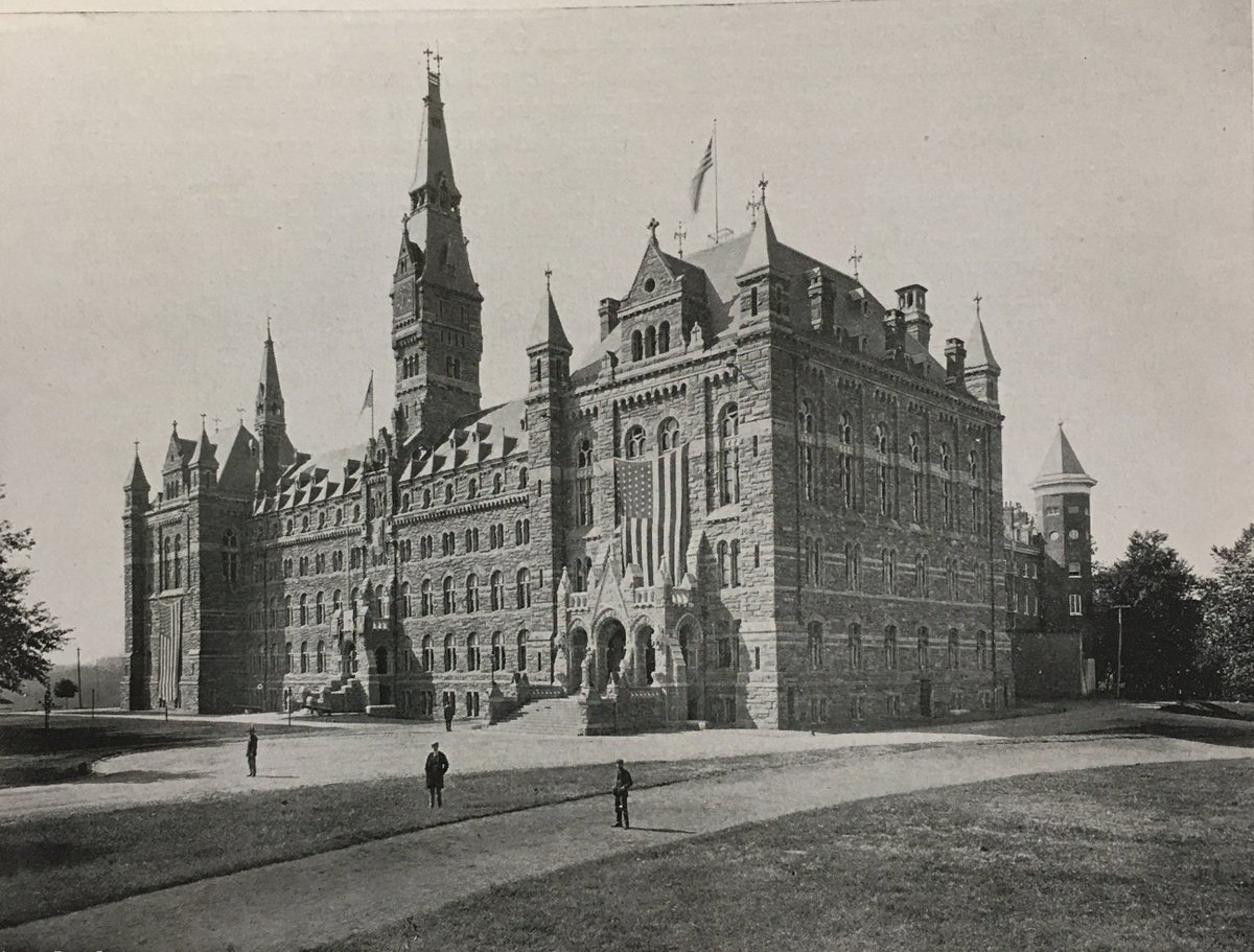 An old, black and white photograph of Healy Hall circa 1908, with three people in the foreground. 