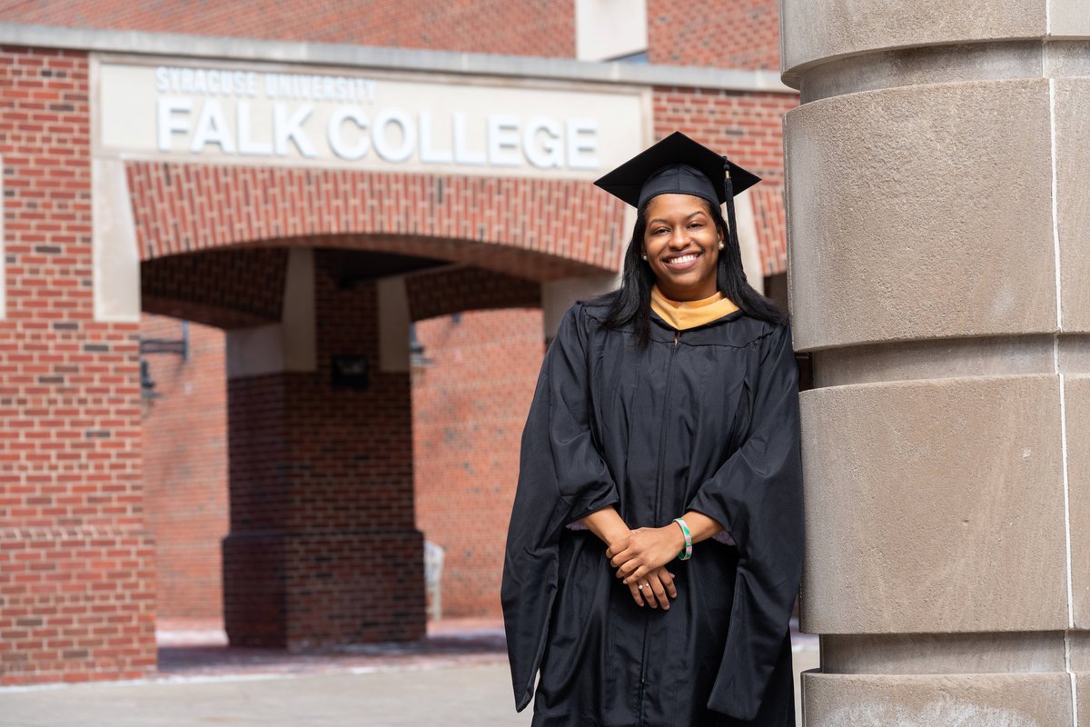 Kennedy Hagens in a graduation cap and gown in front of Falk College