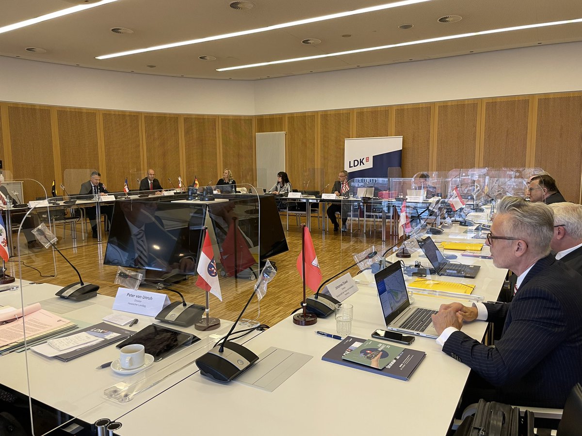 Die Direktor:innen aller deutschen Landesparlamente, des Bundesrates und des Bundestages sitzen in einem großen Konferenzraum in der Bremischen Bürgerschaft. Die Wände sind mit hellem Holz verkleidet, auf jeden Tisch steht die jeweilige Landesflagge sowie Mikrofone, Tablets oder Computer.