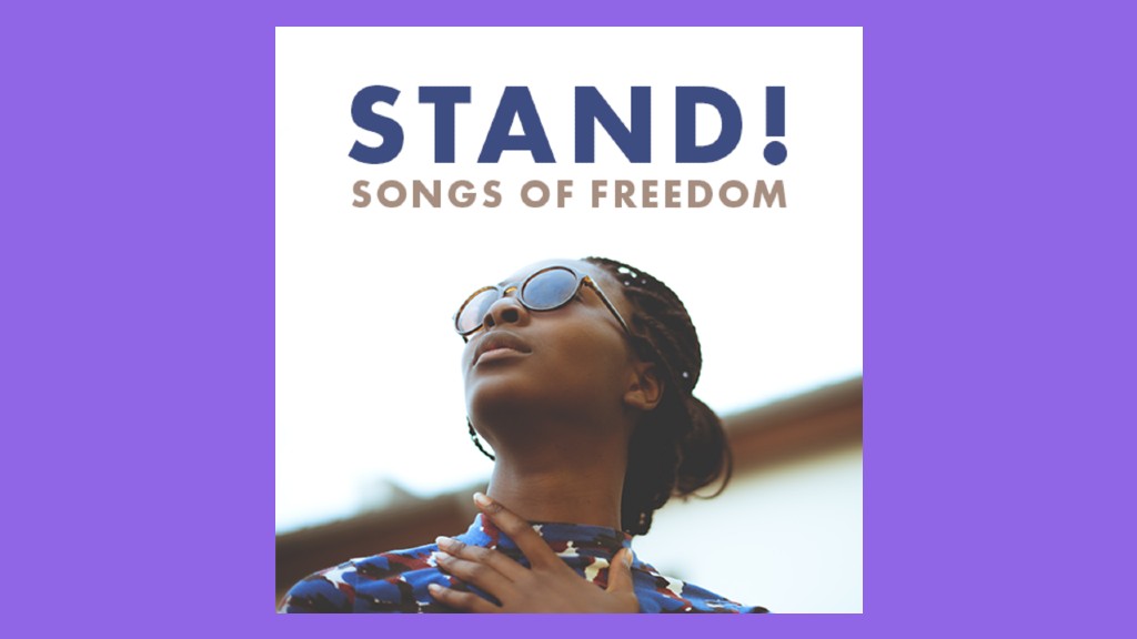 a young black woman standing outside wearing sunglasses looking up with her hand across her heart