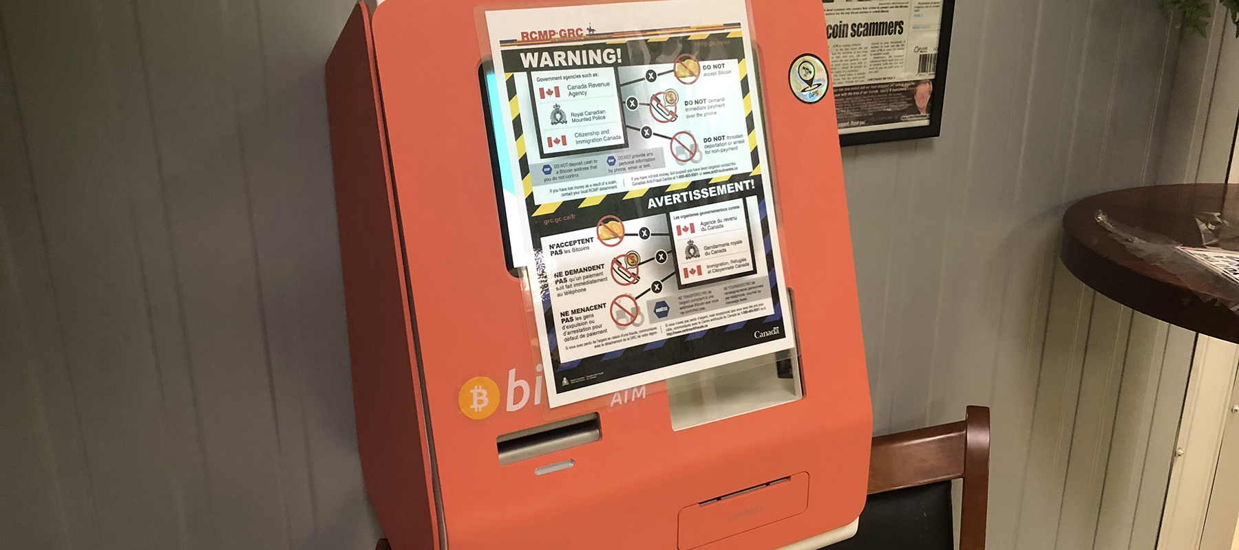 A bilingual warning poster taped to a Bitcoin ATM.