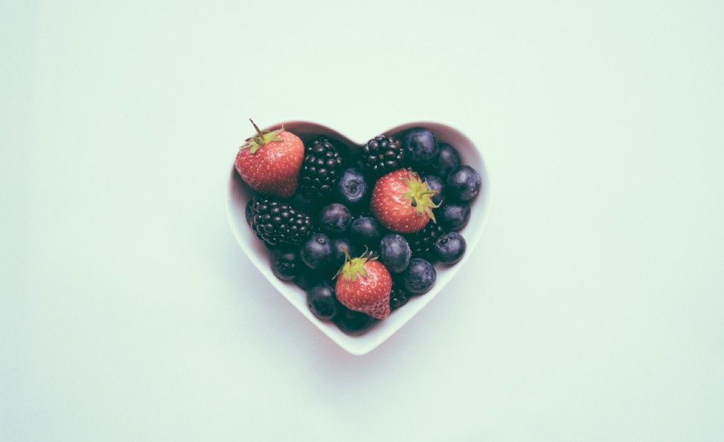 a heart shaped bowl full of berries