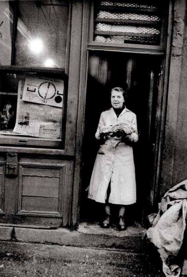 Woman holding a joint of meat in the doorway of a butchers in Spitalfields in 1966