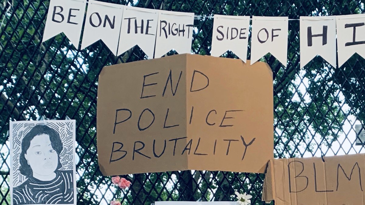 Signs hang on the fence surrounding Lafayette Square outside the White House. One sign shows a drawing of Breonna Taylor. Another says "End police brutality." Another sign says "BLM," while a banner at the top of the fence says "Be on the right side of history," though the end of the word "history" is cut off.