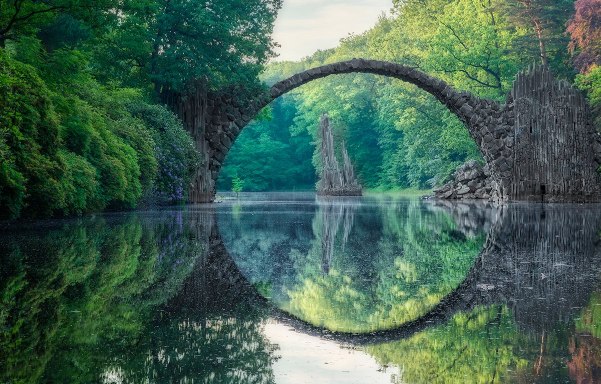 dkeyewitness's tweet photo. Close to Germany's border with Poland, the mesmerising Rakotsbrücke was commissioned in 1860 by a local knight. Known as a 'devil's bridge' (due to the belief that no one other than Satan could have created such a thing), its reflection creates an almost perfect circle. https://t.co/4aBcIhmsx8