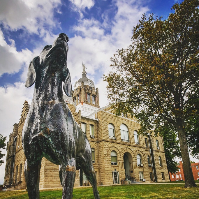 UCMTheatre's tweet photo. One of the first stops for new students and families visiting #UCM is the Old Drum statue that sits on the Warrensburg courthouse lawn. This guy’s the impetus for the famous sentiment, “A dog is a man’s best friend.” Please drop a photo of your dog below! https://t.co/Vtq6BIJRTf