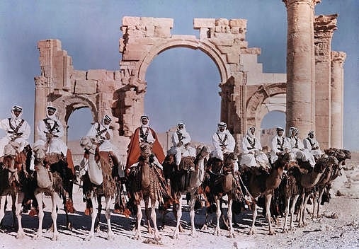 1930, Palmyra, Homs, Syria. Native lines up their camels to ride before the gateway at Palmyra.