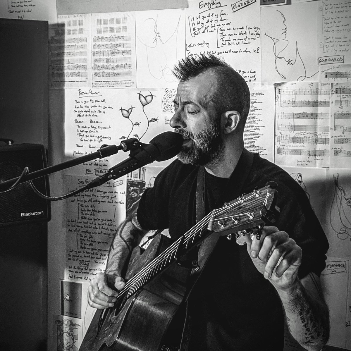jongomm's tweet photo. Rehearsing for Sunday's online gig in front of my serial-killer wall of lyrics and stuff in my studio. The gig will be live on my website, and you need a ticket to get in, but they're Pay What You Want (including free), only from https://t.co/RvFPaQMYPR https://t.co/M0BOimTAJN