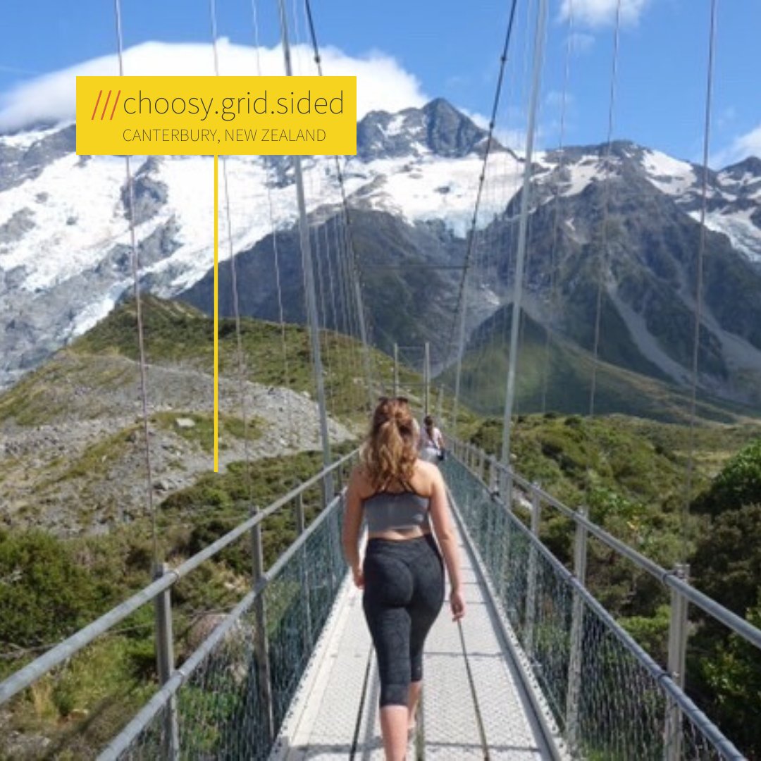 Woman crossing bridge on mountainous terrain. what3words address reads ///choosy.grid.sided