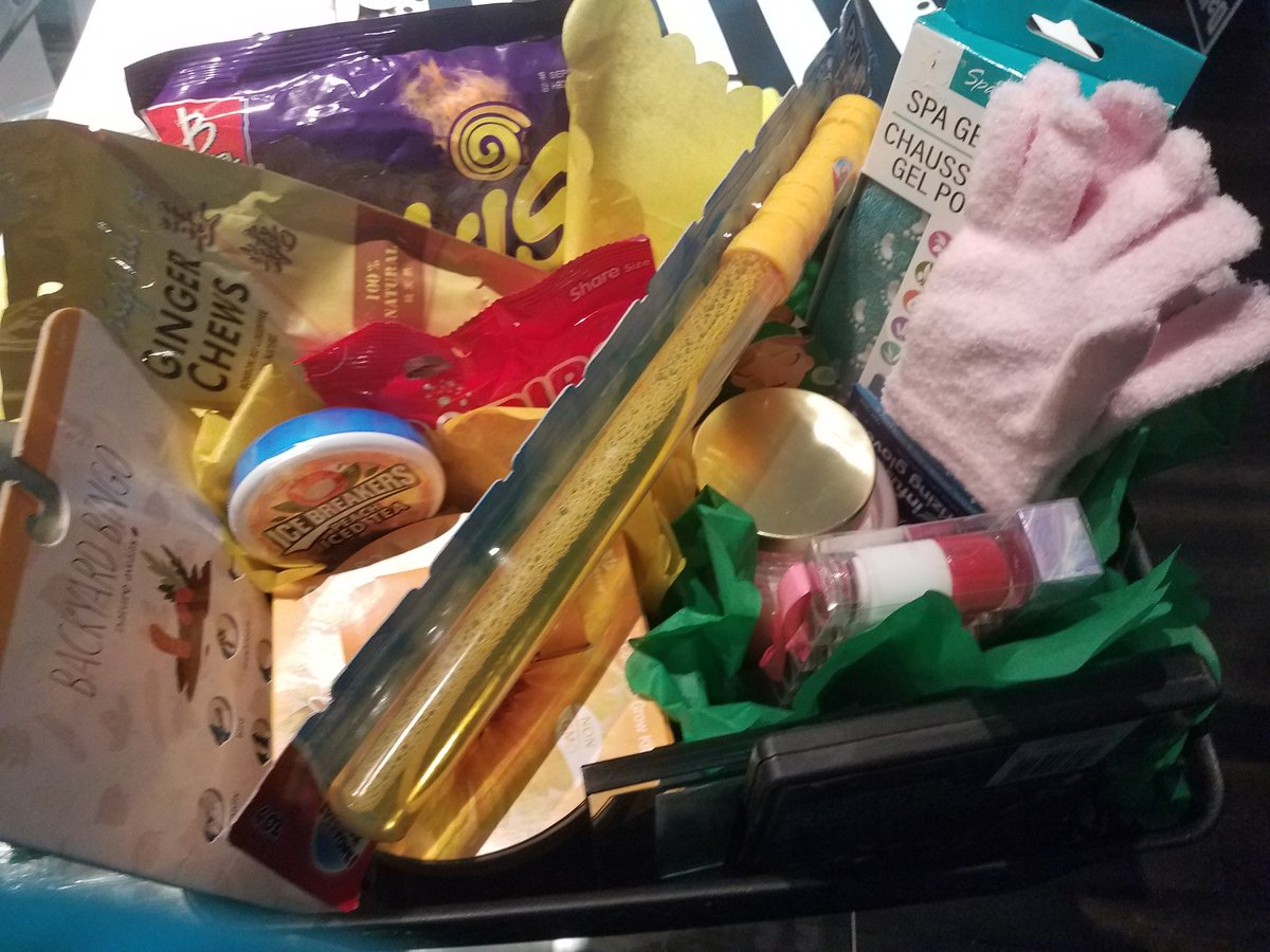 Care package photo containing backyard bingo, ice breakers iced tea mints, ginger chews, Takis chips, a bubble wand, Spa gel gloves and socks, Haribo Gummy Cola, a scented candle