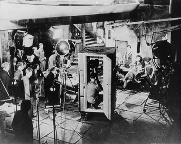 This image from our Kodak Collection shows a “talkie” being made in the studio, with the cine camera encased in a sound-proof booth, so the mics don’t pick up its whirring sound.