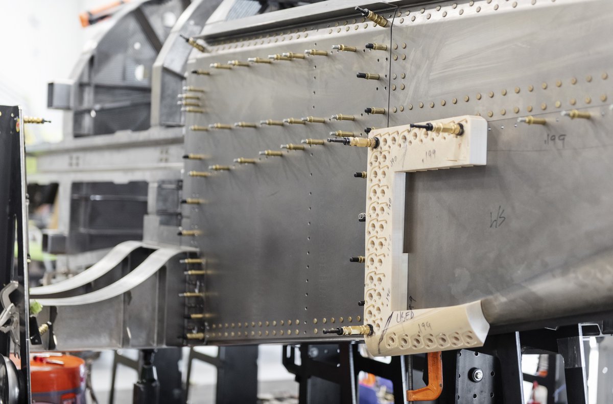 boomsupersonic's tweet photo. XB-1’s build continues in the hangar with the installation of titanium panels on the aft fuselage. We use @Stratasys 3D-printed drill blocks to precisely bore each fastener hole. Follow our progress: https://t.co/uzQNbP1LLy. #aerospace https://t.co/tkDZmudlAu