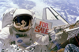 In this image Gardner poses in front of a camera with a "For Sale" sign in his hand, jokingly refering to the broken sats 