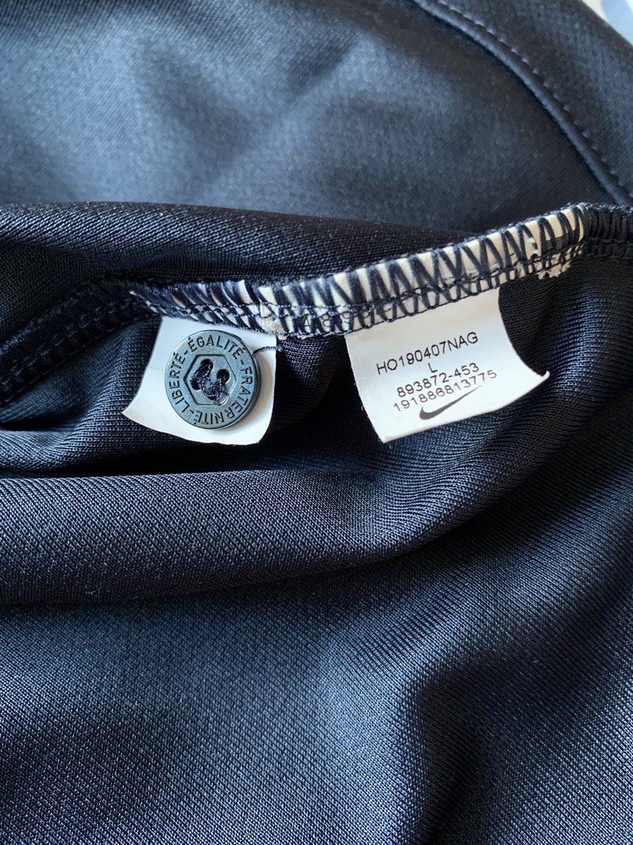 4- À côté de l’étiquette, il y aura un bouton de rechange pour les maillots en possédant un. Vérifiez qu’il y soit, et qu’il soit bien gravé de l’inscription voulue. Certains fabricants de faux mettent un bouton tout simple, parfois même pas de la bonne couleur.