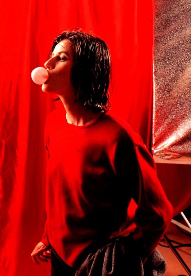irene jacob, wearing a red sweater, blowing bubblegum, three colours: red