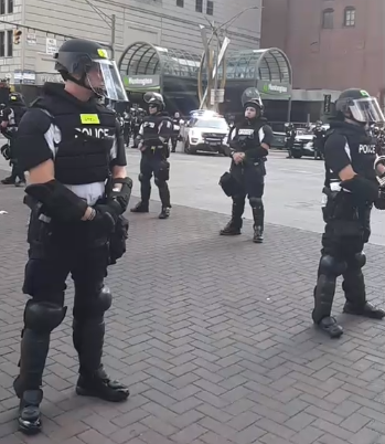 IntrospectOnIt's tweet photo. (picture taken from a live feed) 

If you're going to stand in the road and have the whole thing blocked off...why not just block the road off for the protesters and let them continue peacefully protesting. #columbusprotests #columbusprotest https://t.co/RYlw8WaHAG