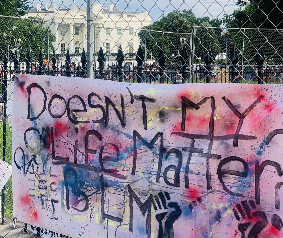 A large sign on a fence outside of the White House says "Doesn't my life matter? BLM."