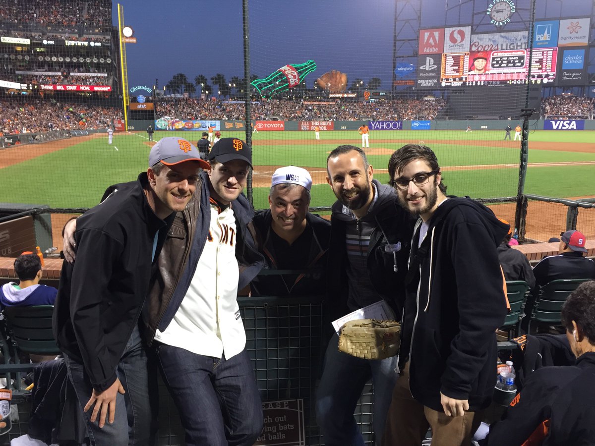 4 iOS developers standing next to Eddy Cue. In the background is a baseball game being played.