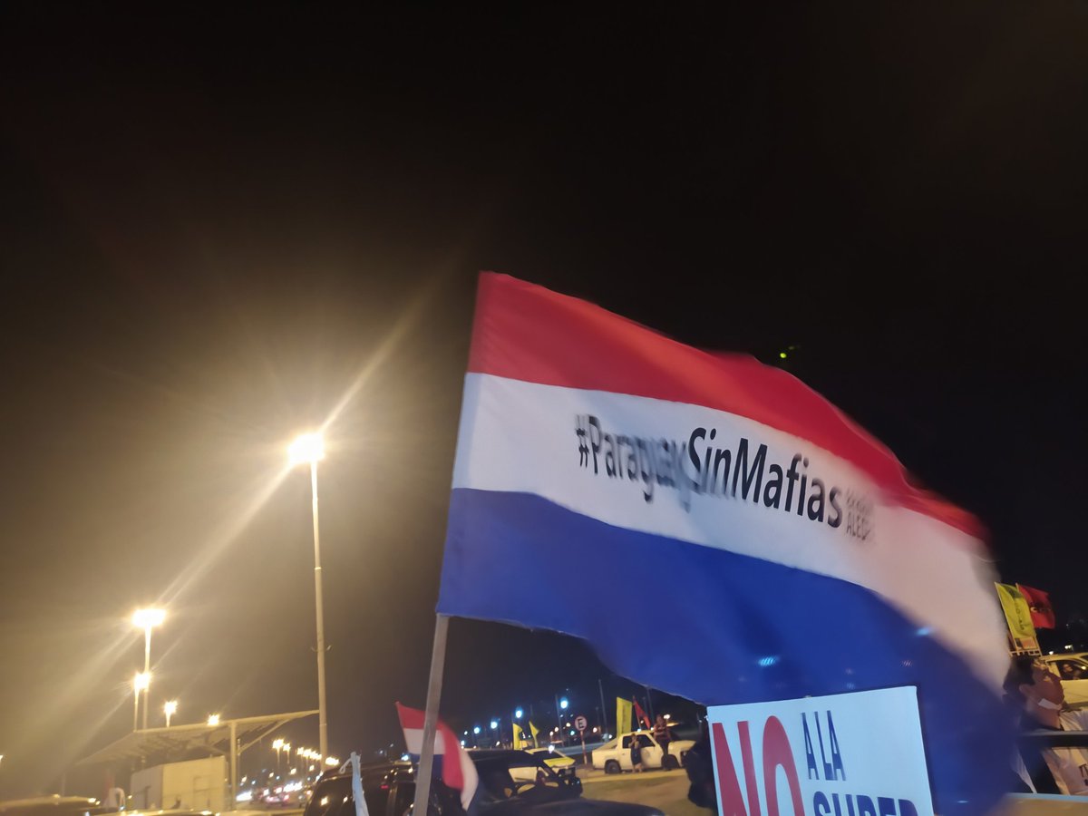 Neengatu_py's tweet photo. Una larga cola de vehículos avanzan lentamente sobre la avenida José Asunción Flores, ante la amenaza de las fuerzas de seguridad que intentan restringir la circulación. A lo largo de la caravana flamean banderas de distintos colores al costado del río Paraguay. https://t.co/tup1s8Cth7