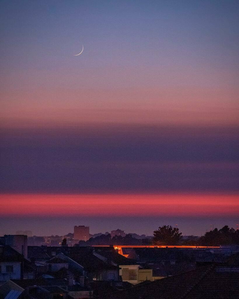 A new Moon sets in Porto after the Sun has set! This photo was taken during the blue hours. The crescent of the moon is in the blue sky. Then colours gradually shift to orange, purple and pink created from the refraction from the water droplets present i… instagr.am/p/CBxS-BIsYOA/