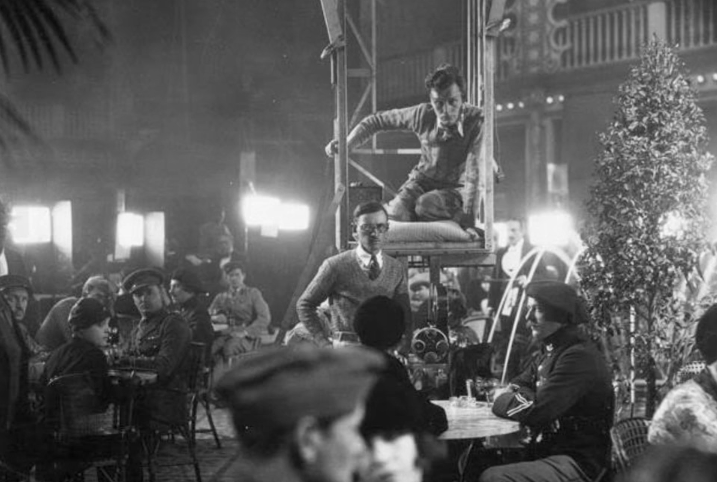To answer some questions before they pop up...The camera is suspended from a platform so it can glide over the tables. The actors move (along with the table) out of the way before the dolly runs them overDoing it any other way would be impractical, as the camera was too heavy