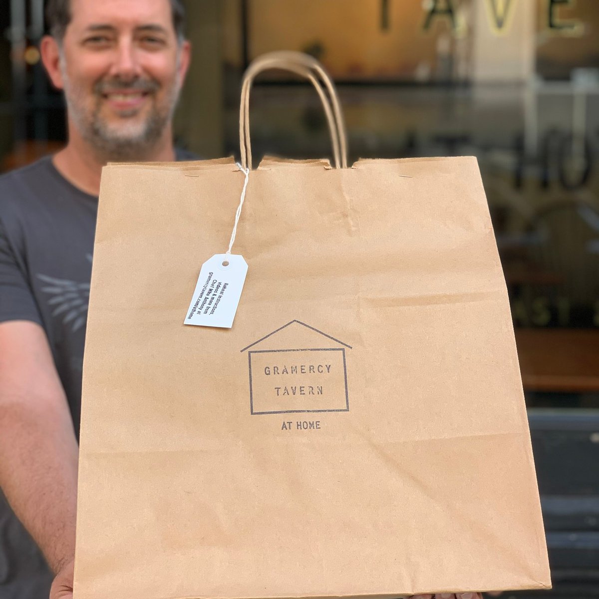 Executive Chef Mike Anthony holding out a Gramercy Tavern at Home bag
