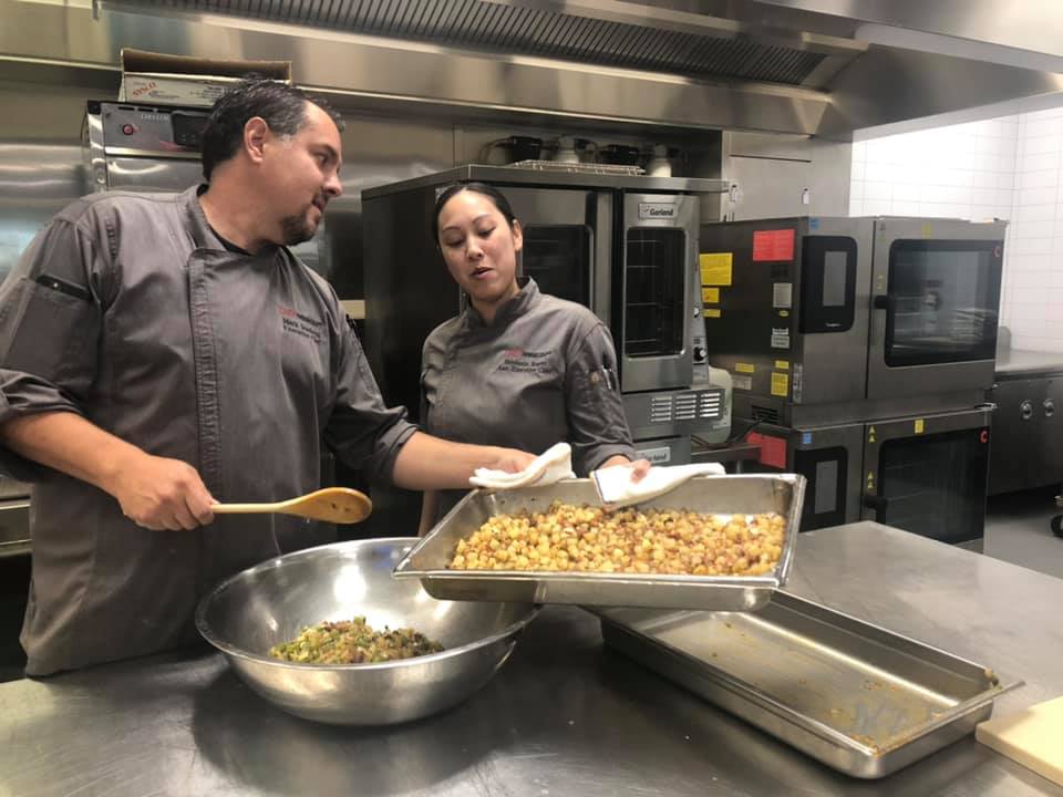 UNLVHospitality's tweet photo. Our chefs Mark &amp; Steph participated in the #24Meals initiative, which provides meals made by local chefs to Las Vegans in need.

Using a box of mystery ingredients, they prepared 24 meals of breaded pork chops on beds of Cajun hash with roasted corn sauce. Way to go, team! https://t.co/r6KcrrR49P