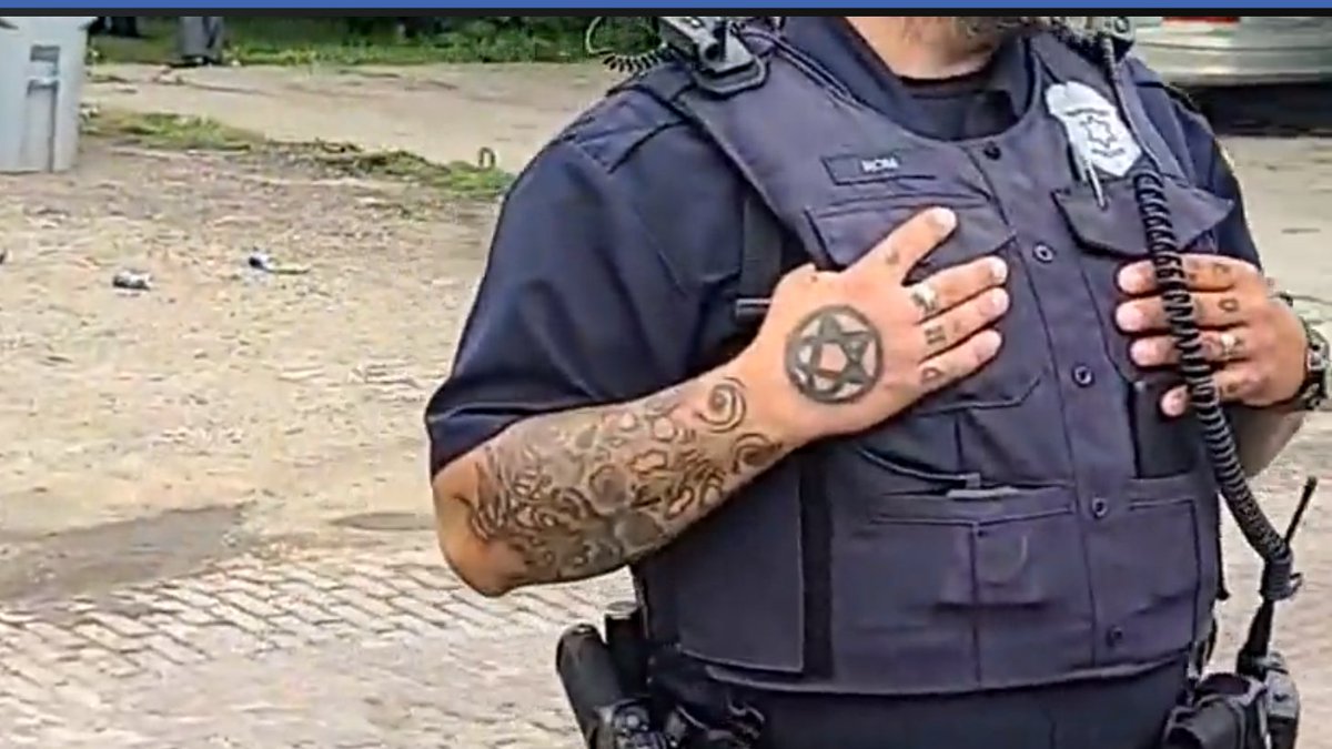 the crowd notices, starts talking about, and vaun zooms in on, this cop's hand tattoo