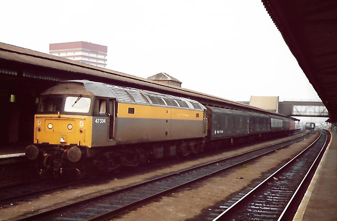 SalopianLyne's tweet photo. Engineer's Dutch Yellow &amp; Grey liveried British Rail Class 47 diesel loco 47334 on a short rake of parcels vans at Reading Station 5/7/91. For several years this loco stalked me everywhere! Gone now though, scrapped 2005 😧 #BritishRail #Reading #trainspotting #Parcels #Class47🤓 https://t.co/rtVxs00TUB