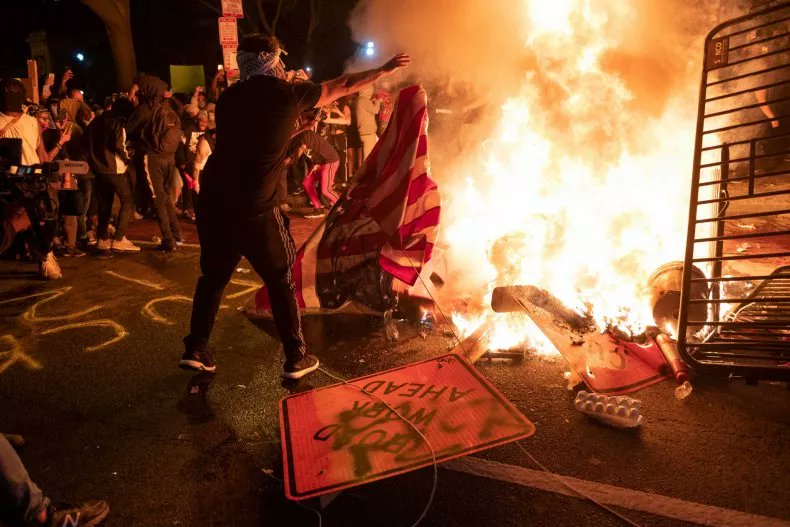 A protester throws a U.S. flag into a burning barricade during a demonstration against the death of George Floyd near the White House on May 31, 2020, in Washington, D.C. Getty Images 