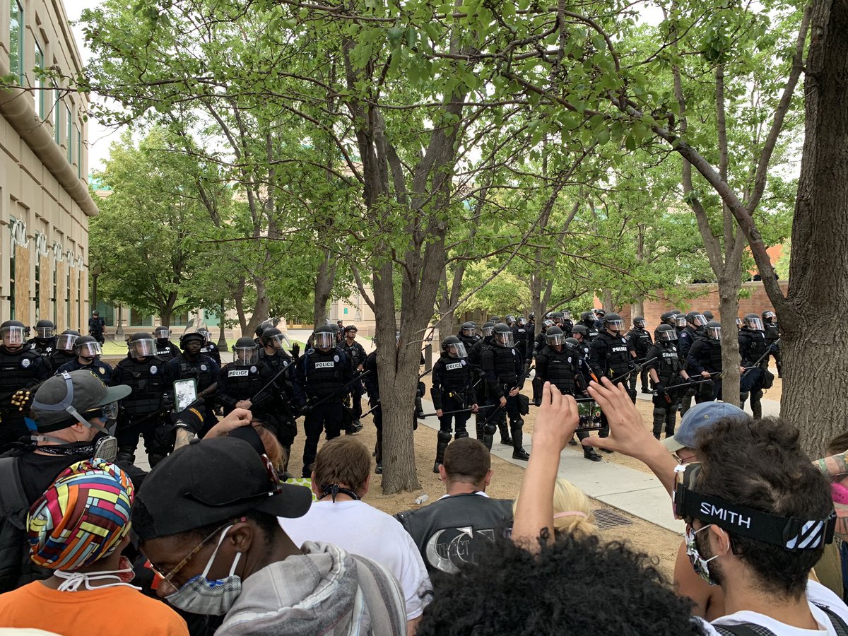 More police officers have lined up behind the first line of officers. Several dozen now in riot gear  #9News