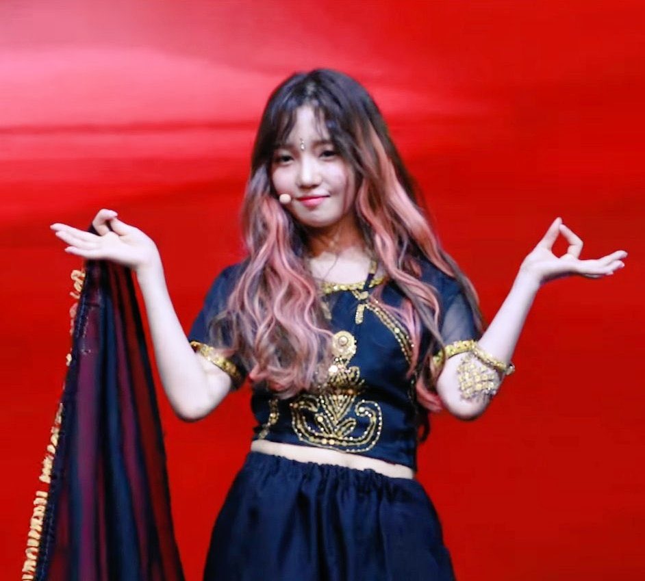 (Fromis_9) Jisun appropriating a mangalasutra ( a jewel given to married women, a bindi and a lehenga while doing mudras and the Namaste hand