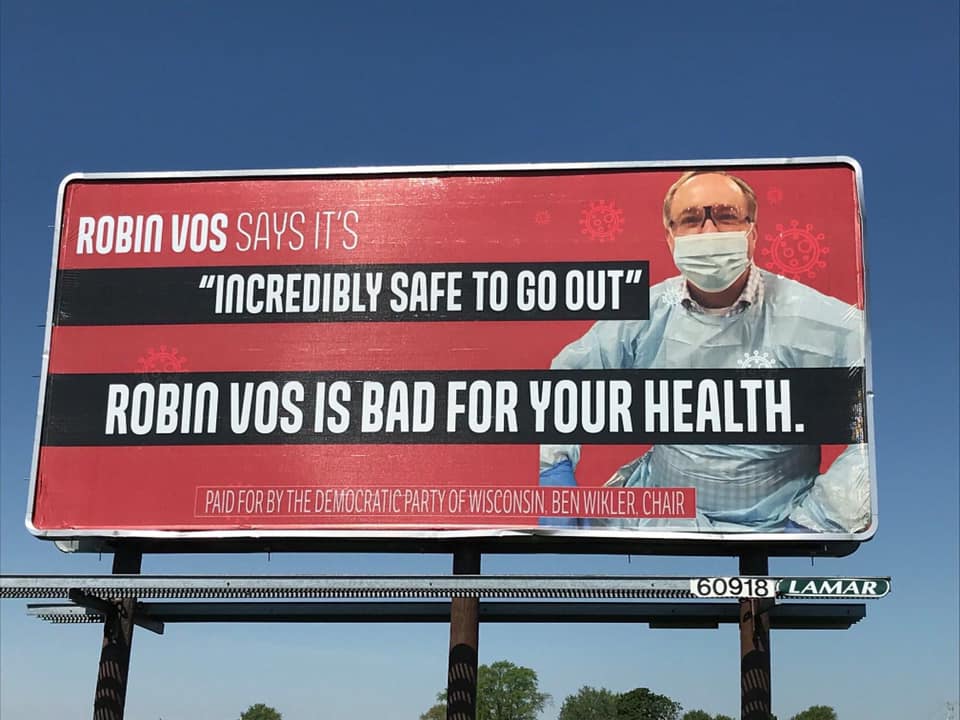 This is the same Robin Vos who forced an in-person election during a COVID peak… and then told reporters it was “incredibly safe to go out” on election day—while wearing full-body PPE.(We put up this billboard about it in his district.)