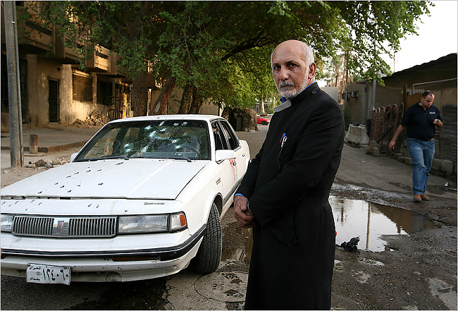 An Armenian priest stands infront of the Oldsmobile car of the two slain women. Baghdad, Iraq 2007.