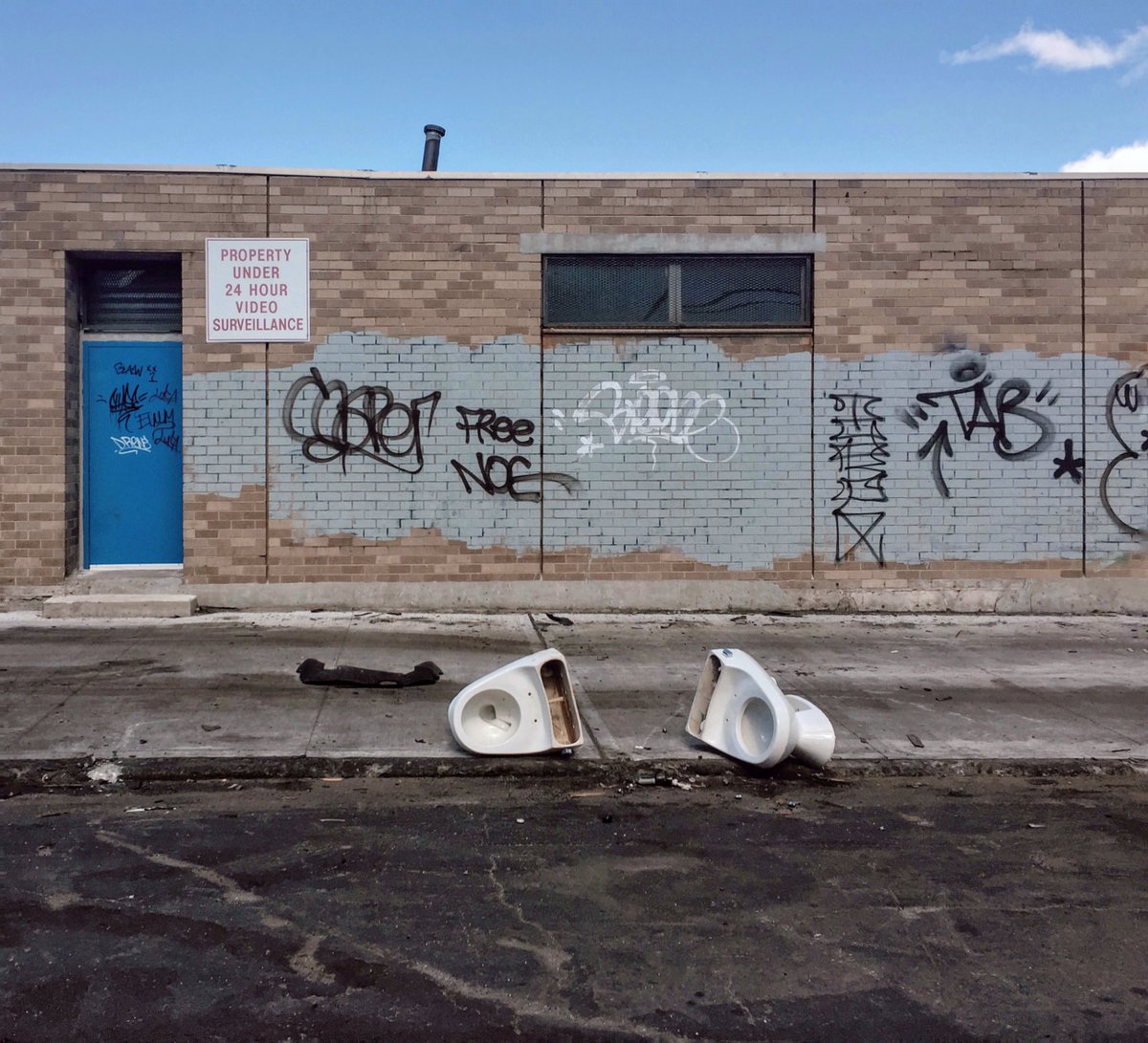 Abandoned toilets beside a building covered in graffiti