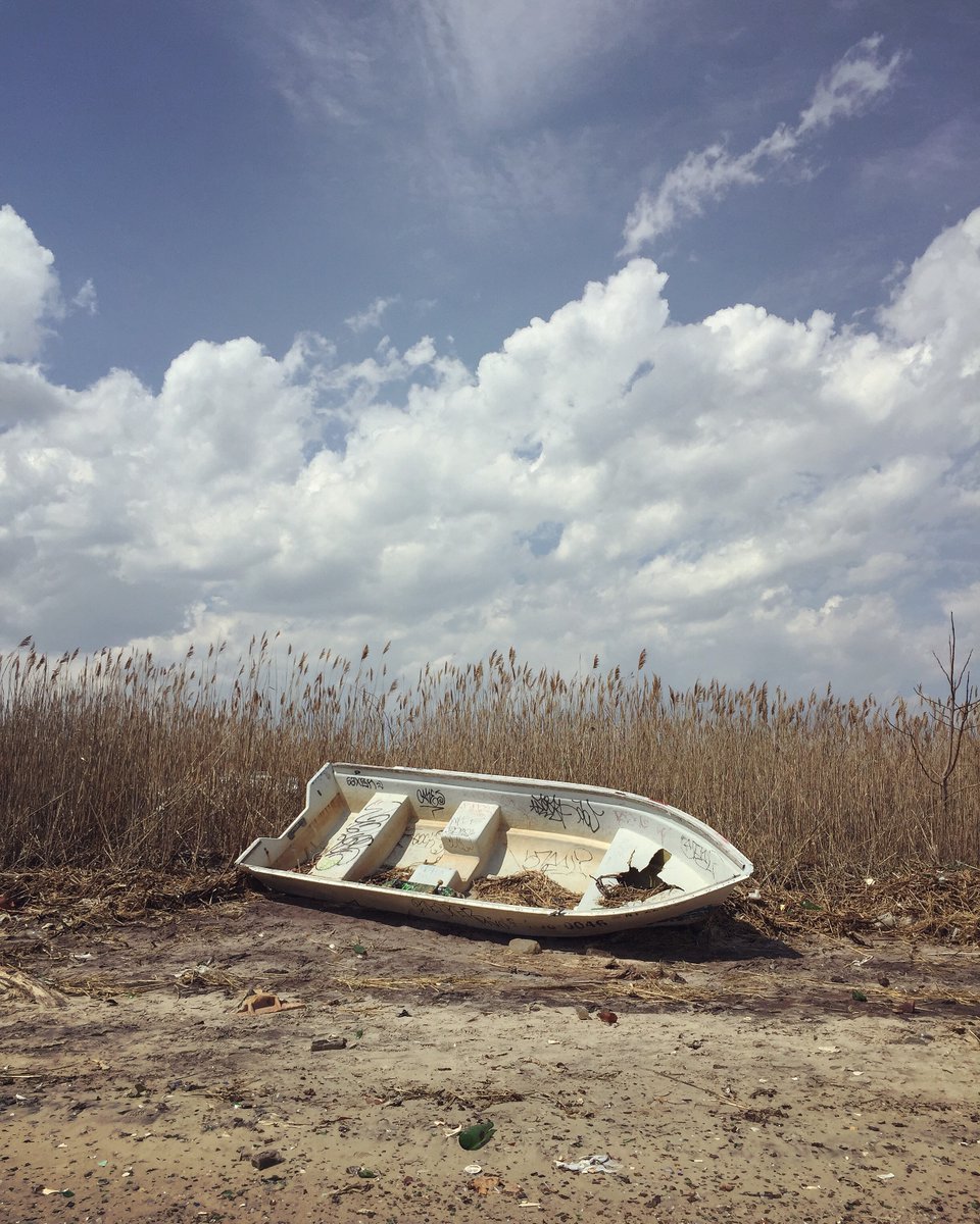 Abandoned boat in a beach with dramatic clouds