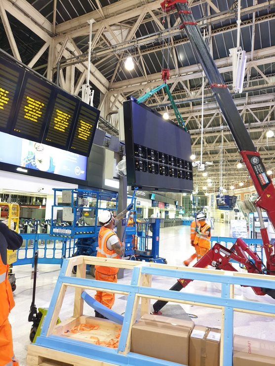 Technicians installing a 3m x 1.5m passenger information display screen at Waterloo station