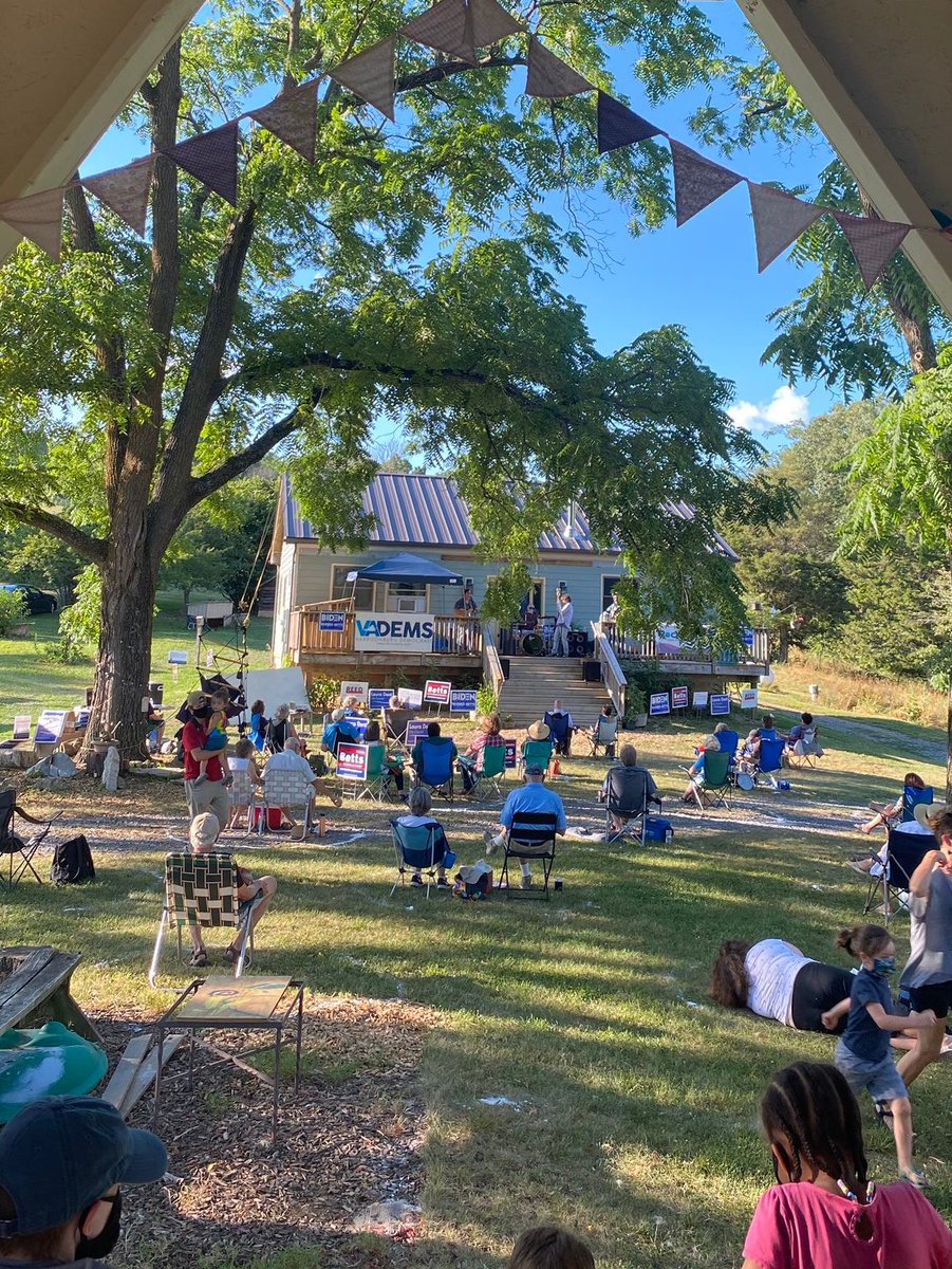 A group of people sit outside in small groups for a Rockingham County Democrats event. 