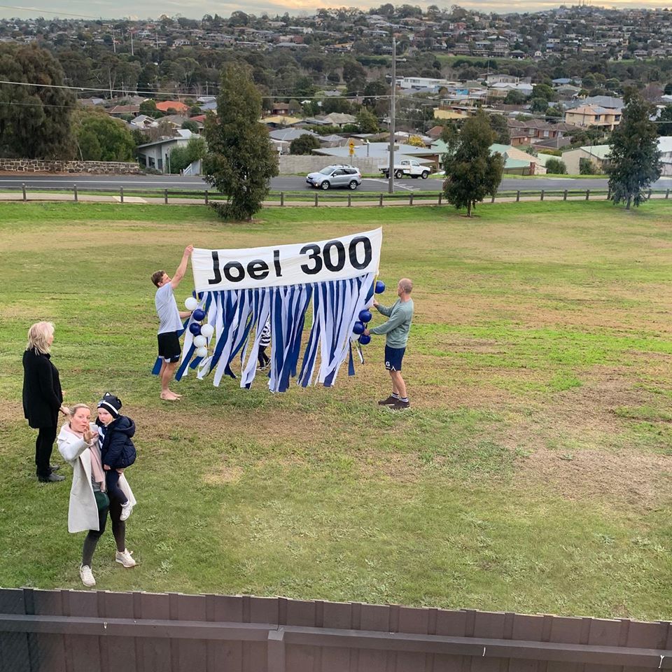 A beautiful photo. With covid restrictions, <a href="/joelselwood14/">Joel Selwood</a> won't get the usual banner today. 

So his mum and dad and the Geelong based clan turned up outside his window with a banner.

Scott and Troy are holding it up.

A great &amp; loving family. A brilliant footballer. #sel300
