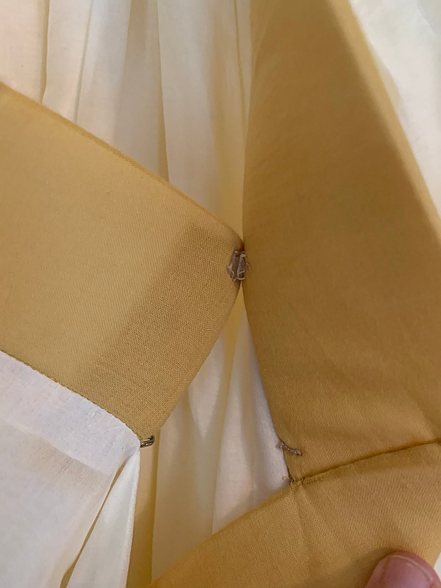 A single snap with a hook and eye on the collar. It& #39;s got structure but it& #39;s... really soft? I think it& #39;s got padding inside. The neckline was completed with this random long piece of fabric because of course it was.