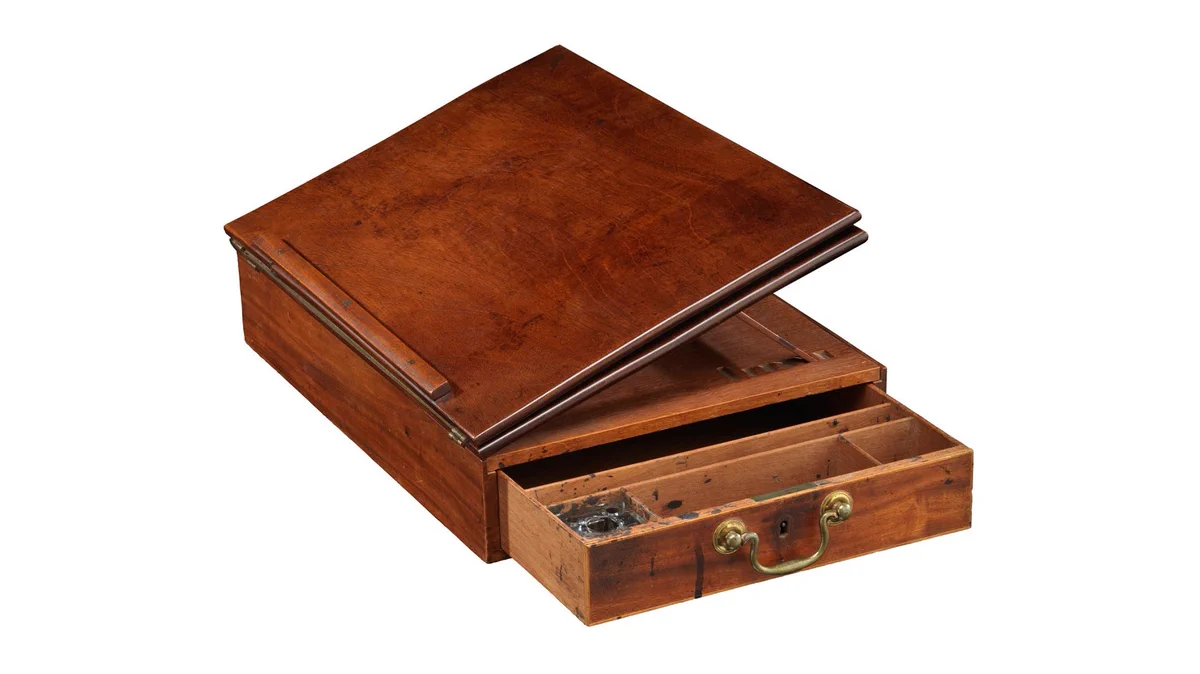 Wooden portable desk with hinged top and drawer on the side.