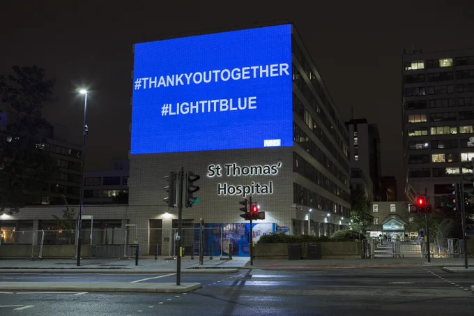 An image of a blue light projected onto St Thomas' Hospital with white writing that says "#THANKYOUTOGETHER" and "#LIGHTITBLUE"