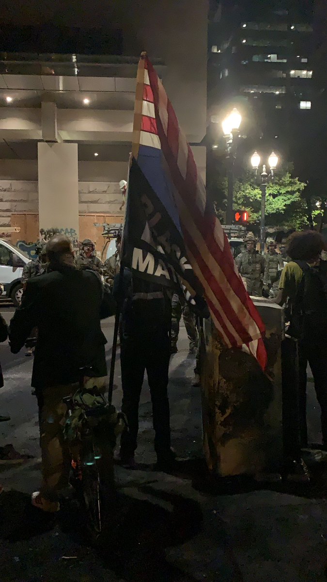 I came to investigate this American flag. Turns out it’s upside down next to a Black Lives Matter sign. The person with the flags is wearing a military... blazer... with all of the badges?? (Idk military terms.) they say they served for many years. They’re yelling angrily @ feds