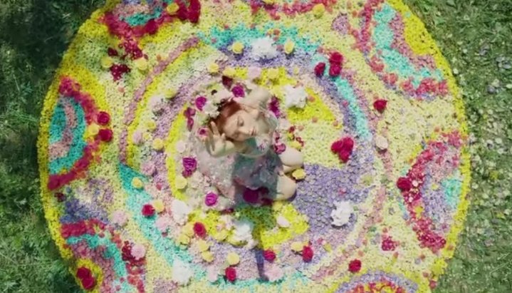 (Chungha) there seems to be a circle of flowers she's standing on. it's called 'pookalam' it's a part of a festival called 'Onam' it is a Hindu festival celebrated in Kerala, India.