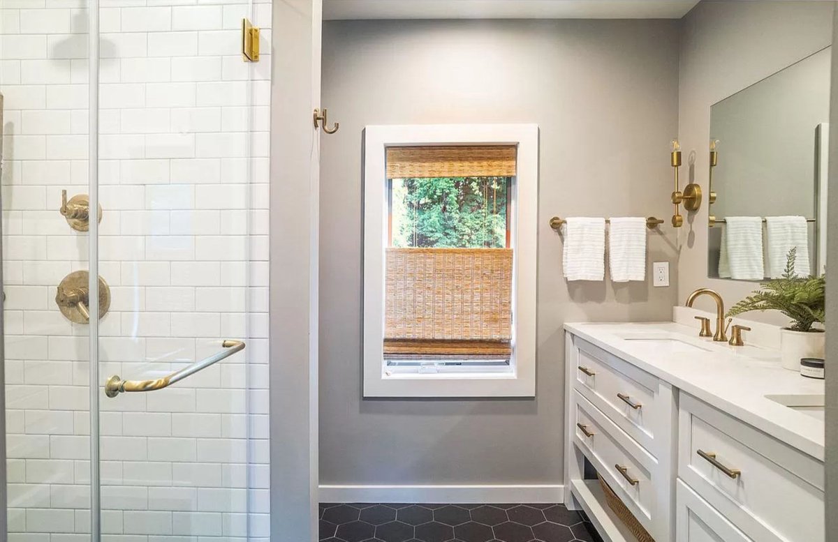 We wish we had more photos of this gorgeous master bath! White with champagne bronze fixtures keeps this space feeling bright and airy while the dark tile and neutral walls provide balance ✨ #cabinetdesignerskingston