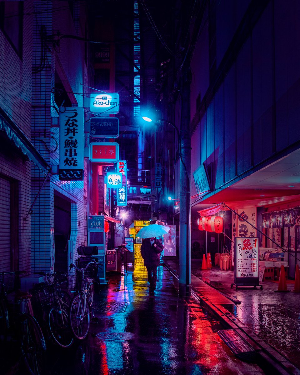 Images from Liam Wong's art and photography book of Tokyo at night. A man walking down the middle of an alleyway on a rainy night holding an umbrella.